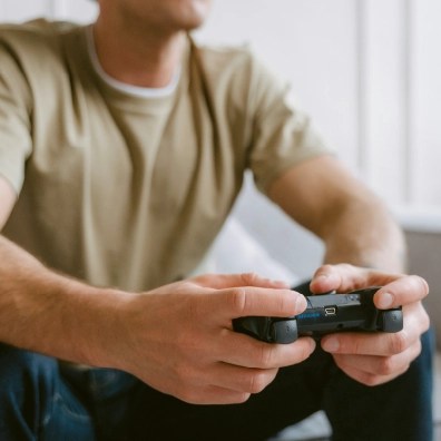 A male holding a remote controller for a video game while sitting down.